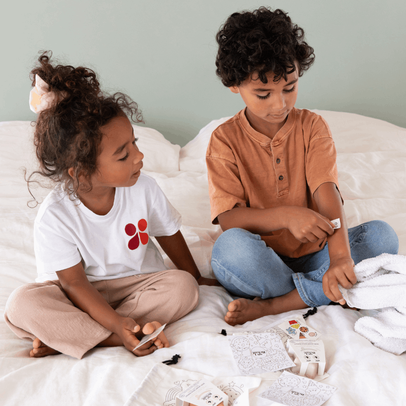 Pochon super kids avec un pochon de toilette en coton coloriable, un coloriage, un set de tatouages avec des messages pour redonner confiance aux enfants, un soin lavant doux en forme d'étoile